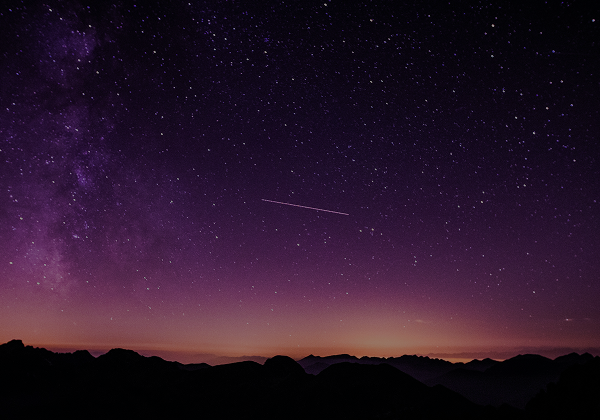 A purple night sky glowing above mountain silhouettes
