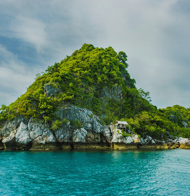 A green island cliff surrounded by turquoise water