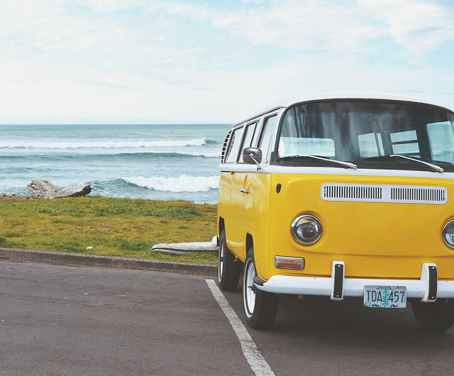 A yellow van parked near the ocean