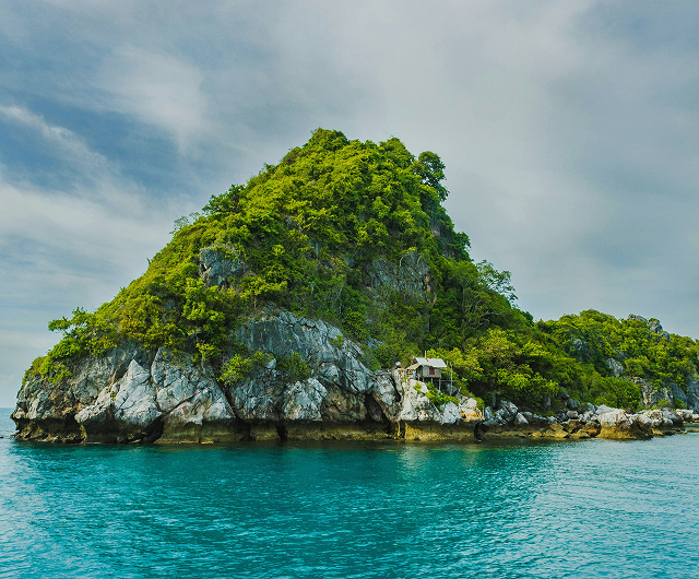 Green tropical island rising from clear blue water